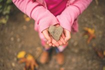 Close-up of Girl holding heart shape stone — Stock Photo