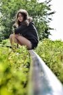 Девушка, сидящая на заброшенной железной дороге в сельской местности — стоковое фото