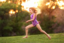Little girl wearing swimsuit jumping in back yard — Stock Photo