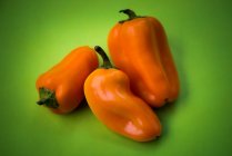 Orange bell peppers on green background — Stock Photo