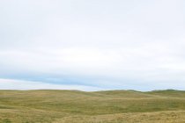 Vue panoramique sur les collines herbeuses sous un ciel nuageux — Photo de stock
