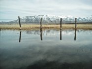 Vista panorámica de la cerca de alambre que refleja en el lago - foto de stock