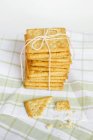 Stack of wholewheat crackers tied with rope on kitchen towel — Stock Photo
