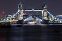 Scenic view of Tower Bridge at night opening with boat sailing below, London, England, UK — Stock Photo