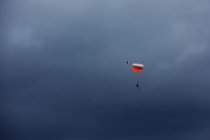 Man paragliding mid air in cloudy sky — Stock Photo