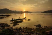 Silhouette di due pescatori in barca sul fiume Mekong, Thailandia — Foto stock
