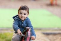 Мальчик сидит на деревянной лошади на детской площадке — стоковое фото