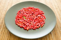 Grüne Chilischote umgeben von roten Chilischoten auf einem Teller — Stockfoto