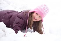 Lächelndes Mädchen, das im Winter im Schnee spielt — Stockfoto