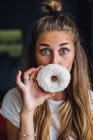 Красивая молодая женщина держит пончик перед лицом — стоковое фото