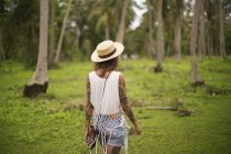 Visão traseira de uma mulher andando em um jardim tropical, Tailândia — Fotografia de Stock
