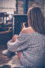 Imagem de visão traseira de mulher atraente com pele bonita em suéter e meias sentadas à lareira em casa — Fotografia de Stock