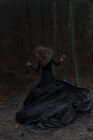 Женщина в длинном черном платье бежит темный лес — стоковое фото