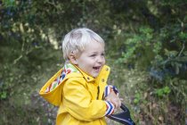 Портрет усміхненого маленького хлопчика в плащі на відкритому повітрі — стокове фото