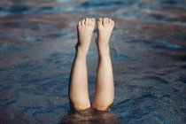 Image recadrée de Jambes d'une fille dans une piscine au-dessus de l'eau — Photo de stock