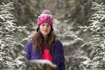 Усміхнена дівчина стоїть в лісі на снігу — стокове фото