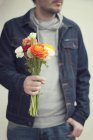 Gros plan de l'homme tenant un bouquet de fleurs — Photo de stock