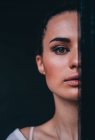 Portrait of a beautiful woman hiding half face behind a curtain — Stock Photo