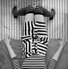 Elevated view of young woman wearing striped clothes and lying on bed, monochrome — Stock Photo