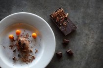 Mousse de chocolate en el plato y barra de chocolate en la superficie gris - foto de stock