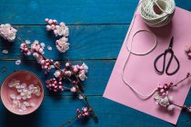 Розовый цветок вишни, ножницы, бумага и нитки — стоковое фото