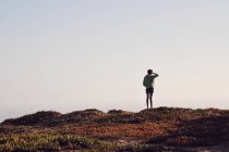 Rückansicht eines Mädchens, das auf einem Hügel steht und die Aussicht betrachtet — Stockfoto