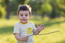 Мальчик держит палку и бежит на улице — стоковое фото