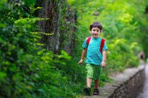 Junge mit Rucksack läuft auf Steinmauer im Park — Stockfoto