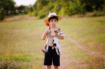 Boy holding fox terrier pup in countryside — Stock Photo