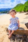 Дівчинка сидить на пляжі і дивлячись на камеру, Оаху, Гаваї, Америка, США — стокове фото