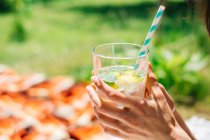 Cropped image of Woman holding a mojito drink against blurred background — Stock Photo
