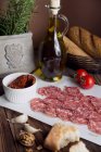 Salami, sun dried tomatoes, bread and olive oil — Stock Photo
