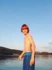Portrait of boy standing on lake shore in summer — Stock Photo