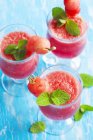 Três saborosos smoothies melancia sobre mesa azul — Fotografia de Stock
