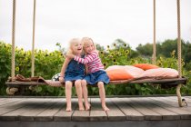 Дві милі сестри обіймаються на гойдалках — стокове фото