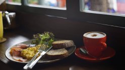Сніданок з чашкою капучино в м'якому легкому настрої з трохи розмитим — стокове фото