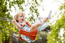 Happy Girl with open mouth on swing — Stock Photo