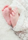 Gros plan de bébé filles pieds enveloppés dans du tissu de dentelle — Photo de stock