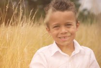 Портрет усміхненого хлопчика, що стоїть на пшеничному полі — стокове фото