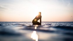 Silhueta de uma mulher sentada na prancha de surf no oceano, Malibu, Califórnia, América, EUA — Fotografia de Stock