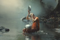 Novice monk cooling off in a creek, Asia — Stock Photo