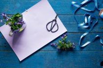 Frühlingsblumen, Schleife, Schere und Papier auf blauem Holztisch — Stockfoto