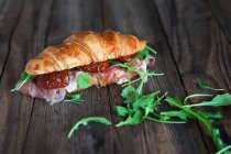 Croissant sandwich with prosciutto, sun dried tomatoes and arugula — Stock Photo