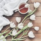 Повышенный вид тюльпанов и чая над деревянным столом — стоковое фото