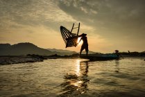 Silhouette eines Mannes, der Fischkörbe in den Mekong wirft, Thailand — Stockfoto