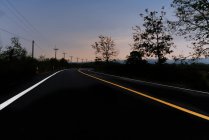 Vista panorámica de la carretera a través del paisaje rural en el crepúsculo, Italia - foto de stock