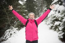 Woman standing in snow with arms in air — Stock Photo