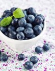 Fresh Blueberries in white bowl with leaves — Stock Photo