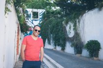 Uomo sorridente in piedi sulla strada con le mani in tasca, Lisbona, Portogallo — Foto stock