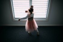 Rückansicht eines entzückenden kleinen Mädchens im Tutu-Kleid, das drinnen tanzt — Stockfoto